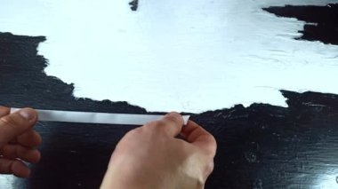 İşçi beyaz bandı ahşap masaya yapıştırıyor.