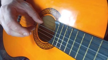 Evdeki adam gitar çalıyor. Erkeklerin elleri ipleri eline alıyor. Müzik yaşam tarzı kavramı yaratır. Herkes için boş zaman hobisi. Retro gitar fotoğrafı.