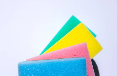 Beyaz arka planda bulaşık yıkamak için renkli süngerler. Yapay lif çevre dostu bir alet değil. Mutfak eşyaları..