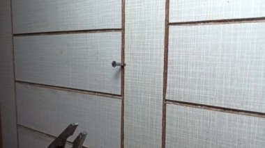 İşçi ahşap duvardan penseyle çivi çıkarır..