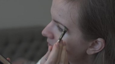Kız makyaj yapıyor. Fırçayla kaş pudrası. Güzellik fotoğrafı konsepti. Yaklaş, 4k.