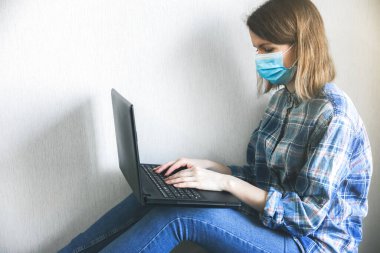 Tıbbi maskeli kadın evde çalışıyor. Karantina zamanında online serbest çalışmalar. Coronavirüs pandemisi. Ekonomik kriz alternatifleri. İşsizlik sorunu olan insanlar. Arama çalışması.