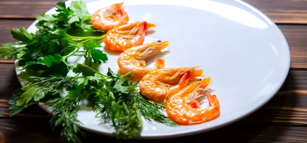 Tabakta pişmiş karides var. Taze dereotlu ve maydanozlu sağlıklı deniz ürünleri..