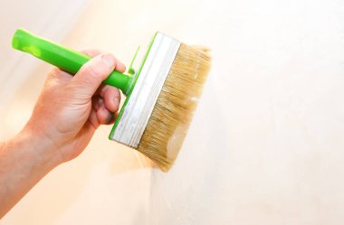 Adam duvara fırçayla yapıştırıcı sürüyor. Duvar kâğıdı asılı. Bakım onarımı dairede tadilat yapıyor. İçerideki restorasyon.