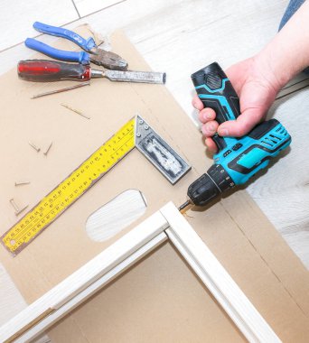 Adam kapıları kuruyor. Marangoz elinde matkap tutuyor. Onarım işe yarıyor. Dairede bakım var..