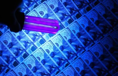 Sahte para ultraviyole lambayla kontrol ediliyor. Dolandırıcılık suçu.