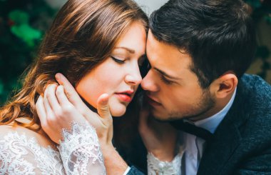 Güzel bir çift kucaklaşması. Yakışıklı damat güzel gelinin yüzünü eline alıyor. Romantik aşk hikayesi. Mutlu insanlar birlikte.