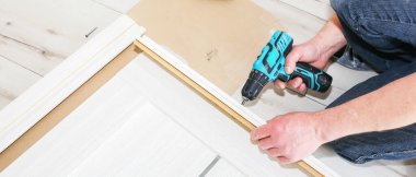 Adam kapıları kuruyor. Marangoz menteşelerde matkapla delikler açıyor. Onarım işe yarıyor. Dairede bakım var..