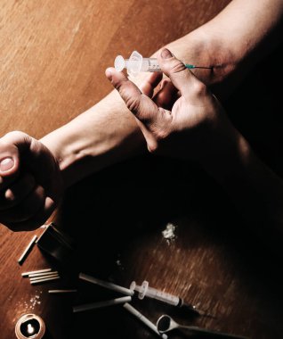 Adam şırıngayla eroin kullanıyor. Uyuşturucu bağımlısı. Mumlar kibrit ve sigarayla yanıyor. Tehlikeli bir alışkanlık. Sağlıksız yaşam konsepti.