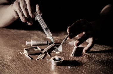 Eroini ateşe veren adam. İğne şırıngası. Uyuşturucu bağımlısı. Mumlar kibrit ve sigarayla yanıyor. Tehlikeli bir alışkanlık. Sağlıksız yaşam konsepti.