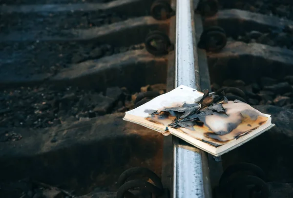Burnt book on the railway tracks. People don\'t like reading. Intellectual problems.