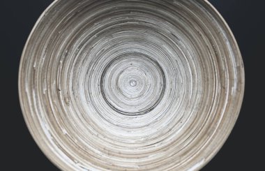 Siyah masanın üzerinde sürekli çizgiler olan orijinal ahşap plaka. Organik, sonsuz çizgileri olan doğal bir kase. Çevre dostu fotoğraf. Açık bej minimalist yerleşim.