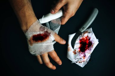 Adam yaraya bandaj yapıştırıyor. Kanama yarası. Bıçakla derin kesik..