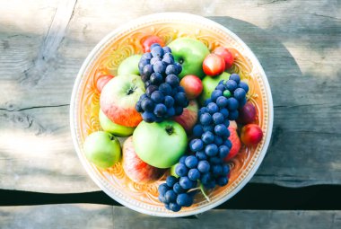 Tahta köprüde meyveli tabak. Kırsal düzlük. Sağlıklı vejetaryen yaşam tarzı konsepti. Yaz titreşimleri. Nehir kenarında piknik.