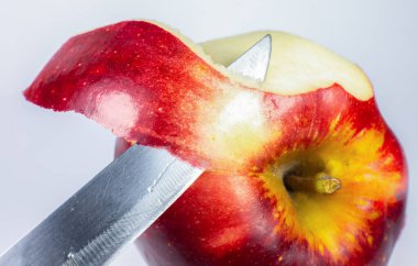 Beyaz arka planda bir bıçakla bir elmayı soymak. Fotoğrafı kapat..