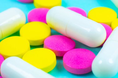 Yeşil arka planda renkli haplar ve tabletler. Kapatın. Tıbbi tedavi kavramı.