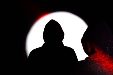 Kapüşonlu adam. Sahne ışıklarının gölgesi.