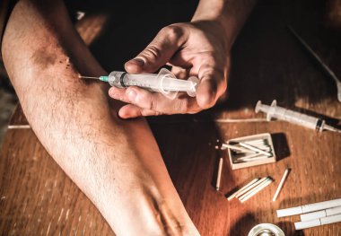 Adam şırıngayla eroin kullanıyor. Uyuşturucu bağımlısı. Mumlar kibrit ve sigarayla yanıyor. Tehlikeli bir alışkanlık. Sağlıksız yaşam konsepti.