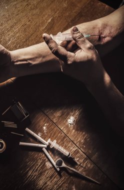 Adam şırıngayla eroin kullanıyor. Uyuşturucu bağımlısı. Mumlar kibrit ve sigarayla yanıyor. Tehlikeli bir alışkanlık. Sağlıksız yaşam konsepti.