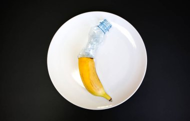 Plastik şişeler ve meyveler tabakta. Hayat tercihi. Kirli yiyecekler yiyen insanlar. Çevresel bir sorun. Ekolojik felaket. Geri dönüşüm sorunu.