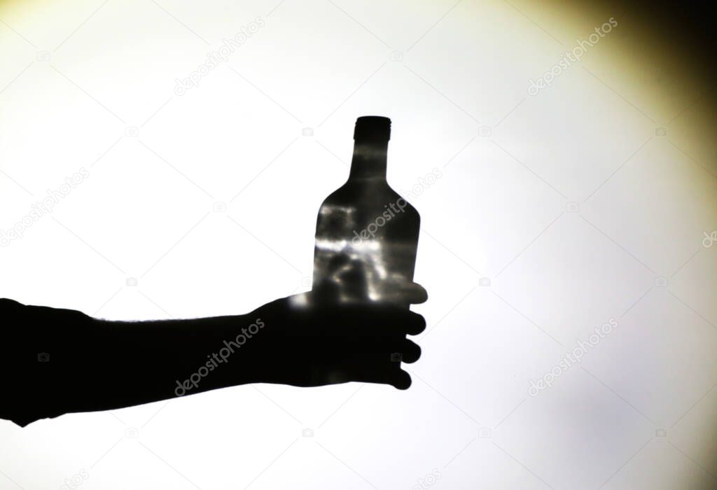 Man's hand with alcohol bottle silhouette.  Alcoholic addict. Dangerous habit. Unhealthy life concept. Social problem.