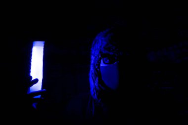 Gece kulübünde neon ışıklı bir gece partisinde maskeli genç bir adam. Bu gece iyi eğlenceler. Tatil eğlencesi. Virüs koruması.