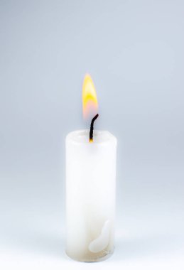 Gri arka planda yanan beyaz mum. Fotoğrafı kapat..