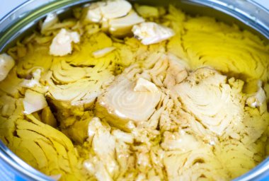 Beyaz arka planda yağlı konserve ton balığı eti. Kutu açıldı, resmi kapat..