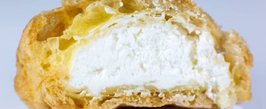 Beyaz tabakta kremalı kek. Kahvaltıda tatlı. Kesilen pastanın yarısının görüntüsünü kapat.