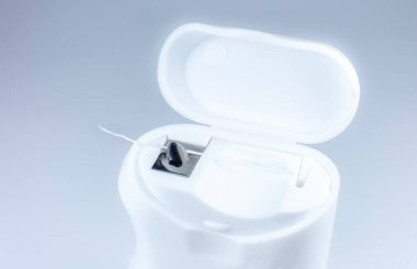 Gri arka planda diş ipi. Kutuyu aç, fotoğrafı kapat..