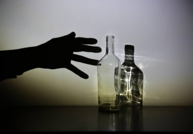 Alkol şişesi silueti olan bir adam eli. Alkolik bağımlısı. Tehlikeli bir alışkanlık. Sağlıksız yaşam konsepti. Sosyal sorun.