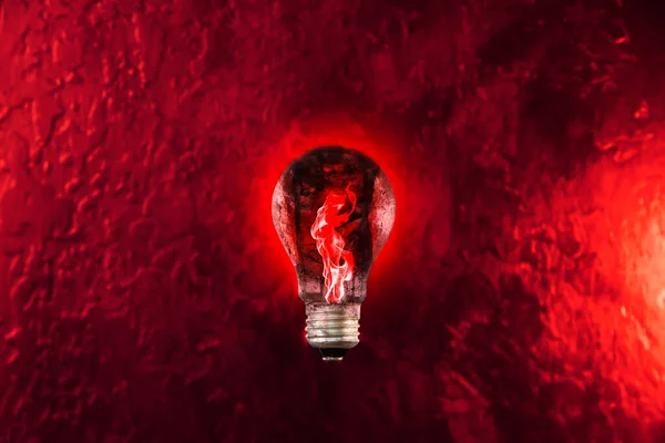 Red fire in the lamp bulb. New idea concept.