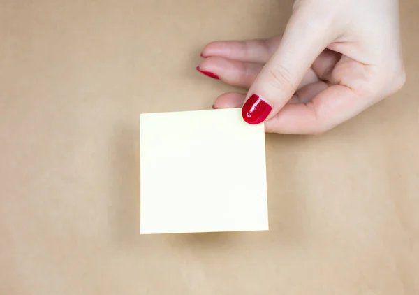 女性の手でリストのステッカーを行うには空白の黄色 クラフトの背景にメモ用紙を閉じる スペースのコピー — ストック写真