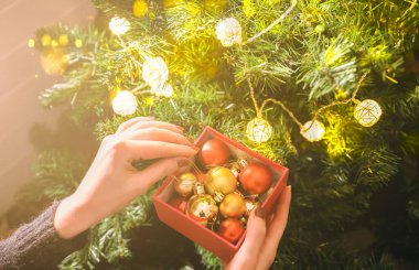 Kız yılbaşı ağacını ışıklarla süslüyor. İçinde kadın oyuncakları olan hediye kutusu. Aşk ve tatil kavramı. Yeni yıl havası. Hygge tarzı. Sihir zamanı.