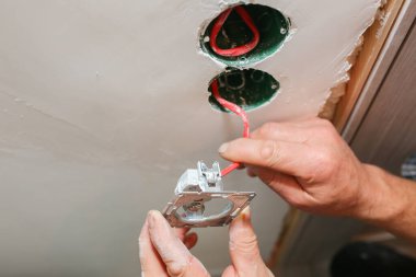 Duvardaki deliklerde soket anahtarı için renkli kablolar var. Adam elektrik yüklüyor. Bakım onarımı dairede tadilat yapıyor. İçerideki restorasyon.