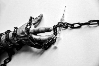 Şırınganın yanında eski paslı zincirlerde bir adamın elleri. Uyuşturucu bağımlısı. Tehlikeli bir alışkanlık..