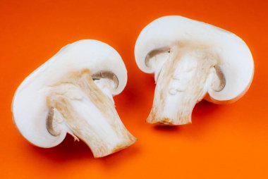 Şampiyon mantarlarının turuncu arka plandaki fotoğrafını kapat. Mantar ikiye bölünmüş, içeride, makro manzaralı..