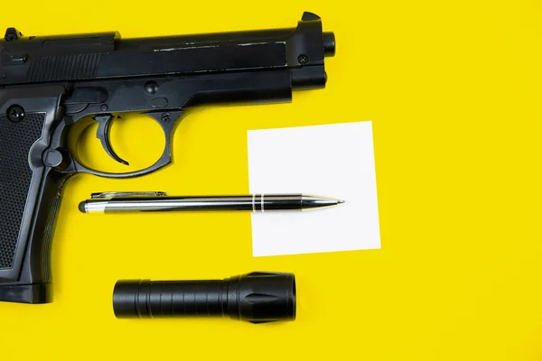 Pistola Negra Papel Recordatorio Bolígrafo Linterna Encuentra Sobre Fondo Amarillo — Foto de Stock