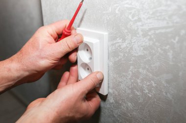 Adam soketi takıyor. Dairede elektrik bakım onarımı yapılıyor. İçerideki restorasyon.