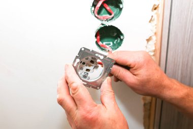 Duvardaki deliklerde soket anahtarı için renkli kablolar var. Adam elektrik yüklüyor. Bakım onarımı dairede tadilat yapıyor. İçerideki restorasyon.