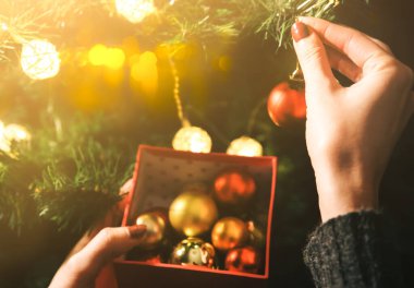 Kız yılbaşı ağacını ışıklarla süslüyor. İçinde kadın oyuncakları olan hediye kutusu. Aşk ve tatil kavramı. Yeni yıl havası. Hygge tarzı. Sihir zamanı.