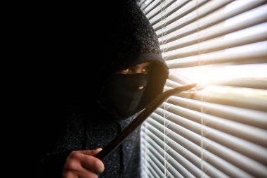 Levyeli bir suçlu pencereden gözetliyor. Eski panjurlar.