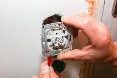Duvardaki deliklerde soket anahtarı için renkli kablolar var. Adam elektrik yüklüyor. Bakım onarımı dairede tadilat yapıyor. İçerideki restorasyon.