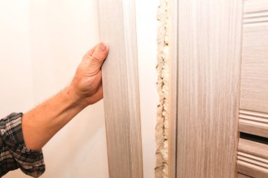 Adam sprey köpükle kapıyı kuruyor. Onarım işe yarıyor. Dairede bakım var..