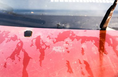 Kaputunda çizikler olan eski bir araba. Araçta soyulmuş boya..