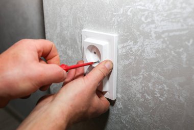 Adam soketi takıyor. Dairede elektrik bakım onarımı yapılıyor. İçerideki restorasyon.