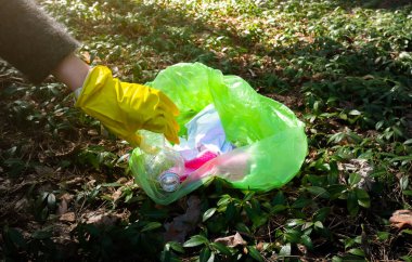 Gönüllüler parktaki çöpü temizliyor. Ormandaki ağaçların etrafında plastik şişe. Enkaz, plastik atık. Çevre Kirliliği. Ekolojik sorun kavramı. Çöpü ve doğanın saçmalıklarını durdurun..