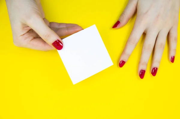 女性の手でリストのステッカーを行うには空白の白 黄色の背景にメモ用紙を閉じます コピースペース ミニマリズム オリジナルで創造的な写真 — ストック写真