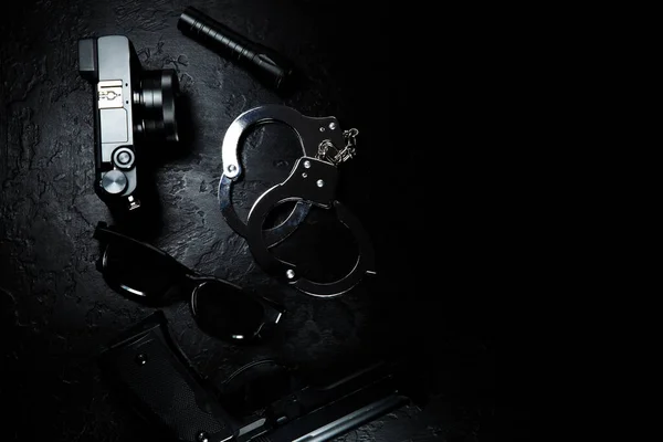 ブラックガン 懐中電灯 メガネ カメラ 警察の金属本物の手錠は黒の背景にあります 私立探偵事務所 情報を探してる 犯罪と強盗刑務所の概念 — ストック写真