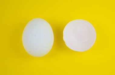 Sarı arka planda beyaz yumurta ve yumurta kabuğu. Uzayı kopyala Minimalizm, orijinal ve yaratıcı fotoğraf. Güzel duvar kağıdı. Paskalya tatili.